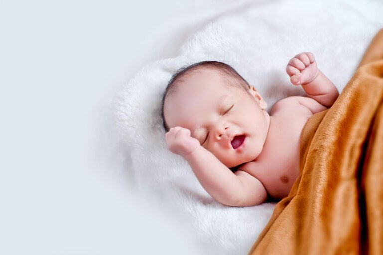 baby lying on white fur with brown blanket